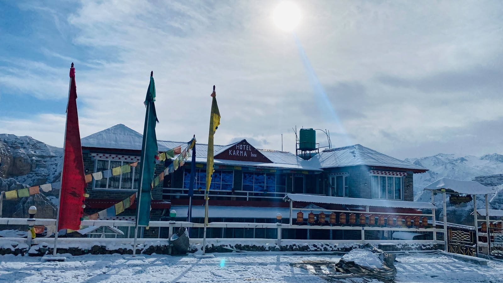 Hotel Karma Inn after a fresh snowfall, prayer flags and snowy peaks in the morning sun, Samar, Upper Mustang