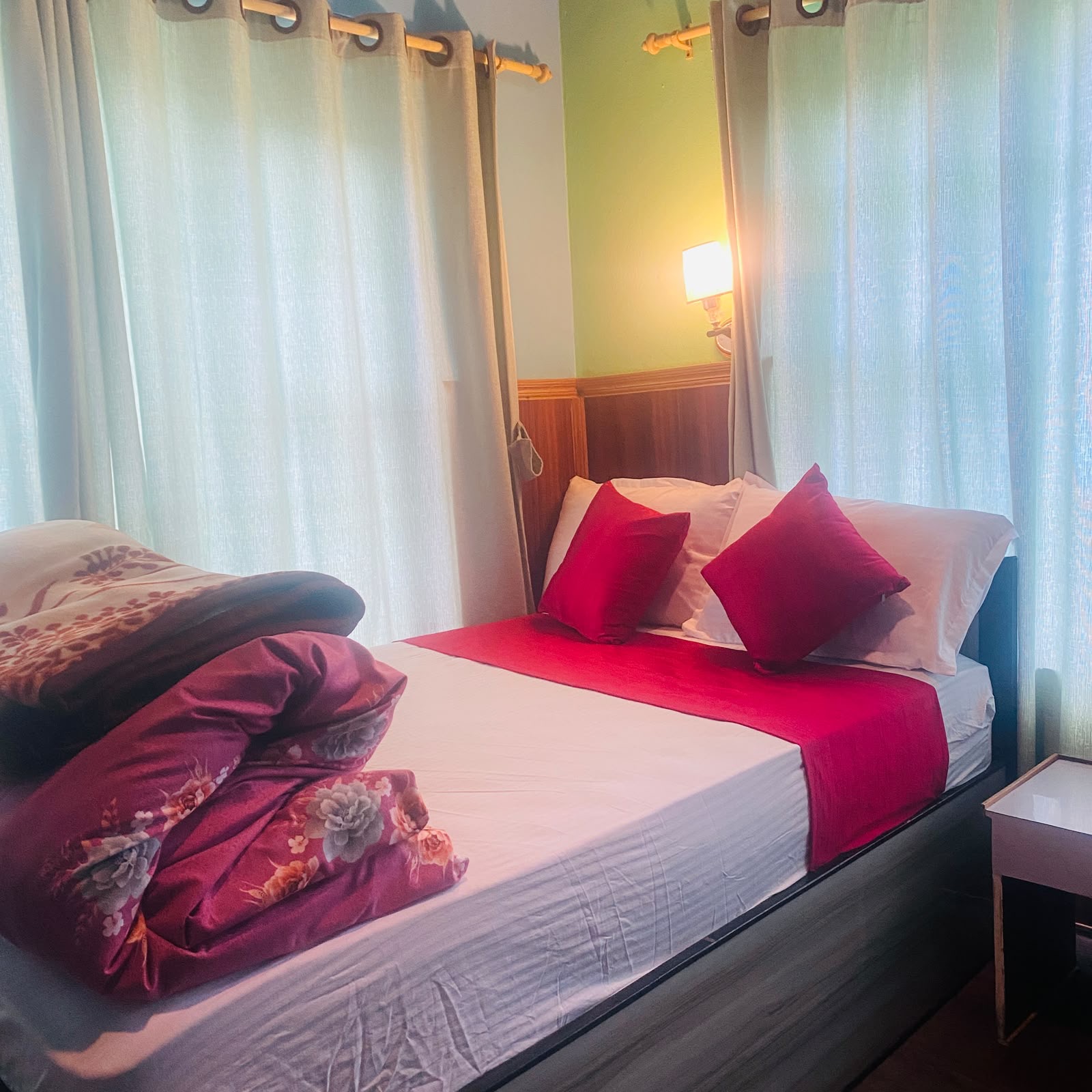 Double room: a wide bed with a red runner beside tall, light-filled windows